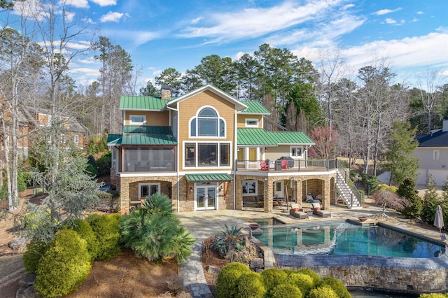 rear view of house with stone siding, a standing seam roof, and metal roof