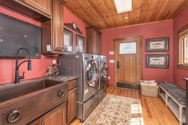 washroom featuring a sink, wood ceiling, light wood-type flooring, cabinet space, and washer and clothes dryer