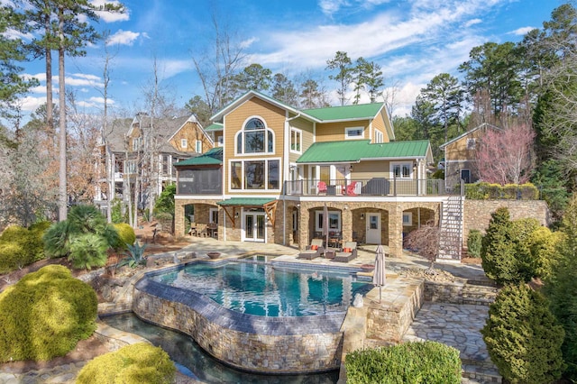 rear view of house featuring stone siding, french doors, a patio area, and a balcony