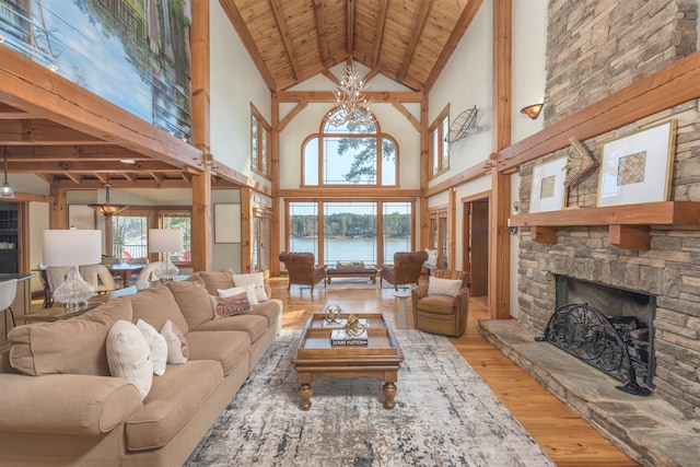 living area featuring wood ceiling, wood finished floors, a water view, a fireplace, and a chandelier