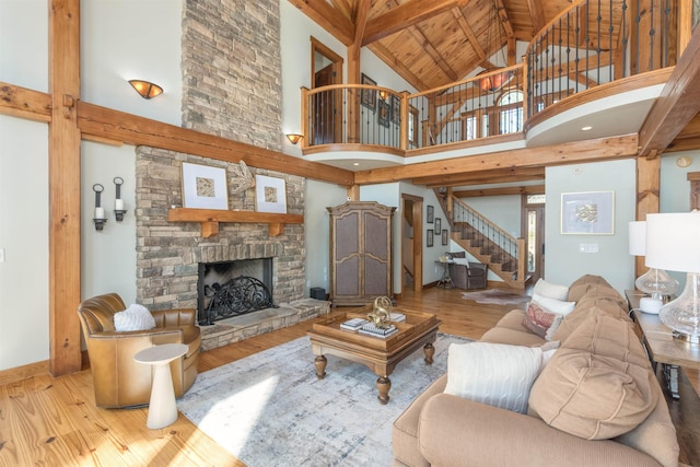 living area with vaulted ceiling with beams, a fireplace, light wood-style flooring, wood ceiling, and stairs