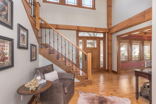 foyer featuring light wood-type flooring, a towering ceiling, baseboards, and stairs