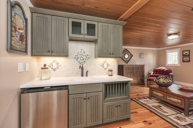 kitchen featuring light wood finished floors, light countertops, backsplash, a sink, and dishwasher