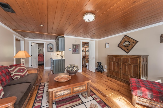 living area with baseboards, visible vents, wood ceiling, crown molding, and light wood-style floors