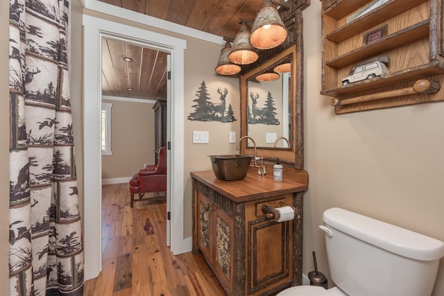 bathroom with toilet, ornamental molding, a sink, wood finished floors, and wooden ceiling