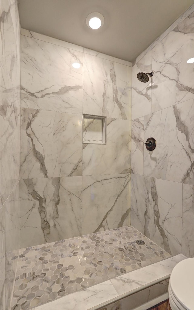 bathroom with a tile shower and toilet