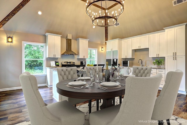 dining space featuring a towering ceiling, sink, a notable chandelier, and dark hardwood / wood-style floors