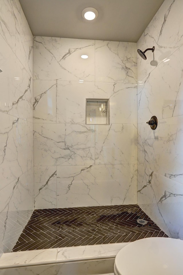 bathroom with tiled shower and toilet