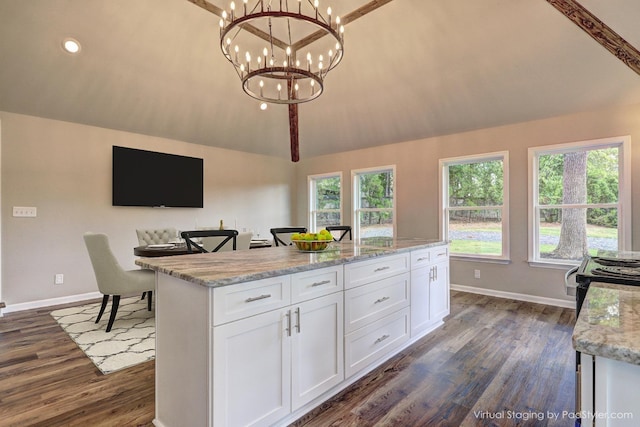 kitchen featuring lofted ceiling, decorative light fixtures, a kitchen island, light stone countertops, and white cabinets