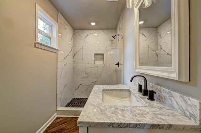 bathroom featuring hardwood / wood-style flooring, vanity, and tiled shower