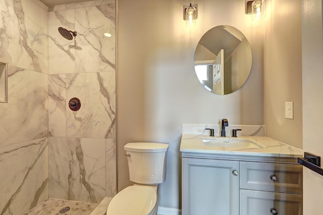 bathroom with vanity, toilet, and tiled shower