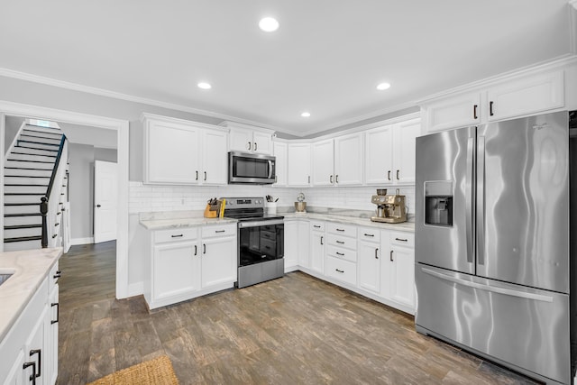 kitchen featuring white cabinetry, ornamental molding, appliances with stainless steel finishes, and light stone counters