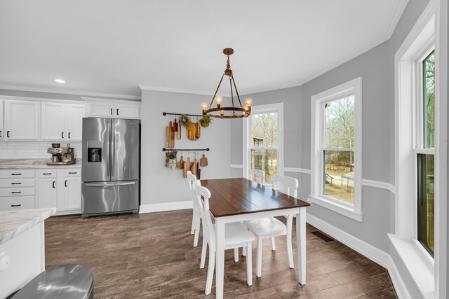 dining space featuring ornamental molding, plenty of natural light, and an inviting chandelier