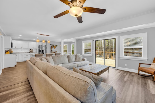 living room featuring crown molding, ceiling fan, and light hardwood / wood-style floors