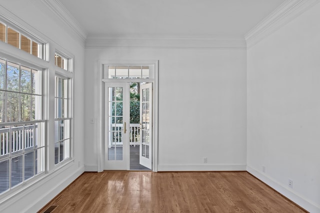 empty room featuring ornamental molding, wood finished floors, visible vents, and baseboards