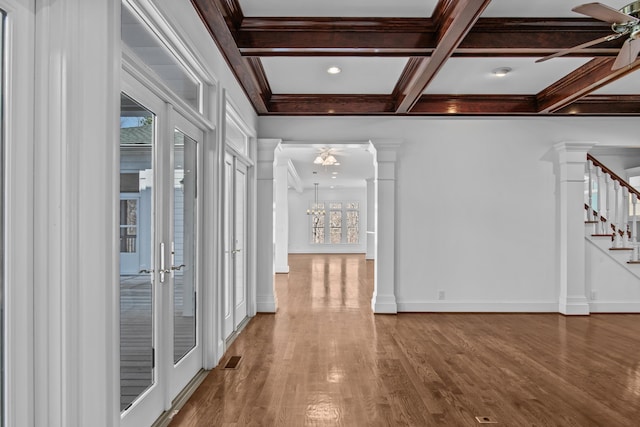 corridor with beam ceiling, decorative columns, stairway, wood finished floors, and coffered ceiling