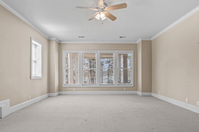 carpeted spare room with ornamental molding, visible vents, ceiling fan, and baseboards