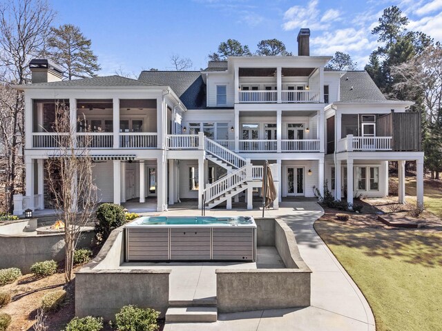 rear view of house featuring french doors, a patio, a chimney, a sunroom, and a balcony