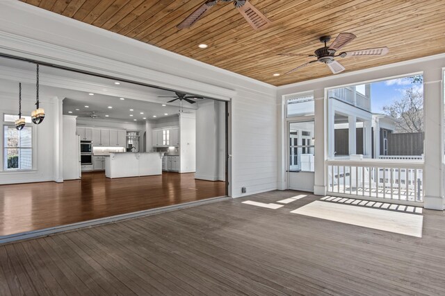 unfurnished living room featuring wood ceiling, ceiling fan, dark wood finished floors, and a wealth of natural light