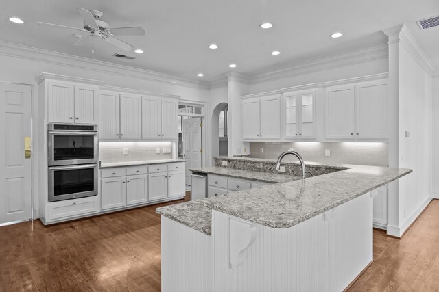 kitchen featuring arched walkways, double oven, visible vents, and white cabinetry