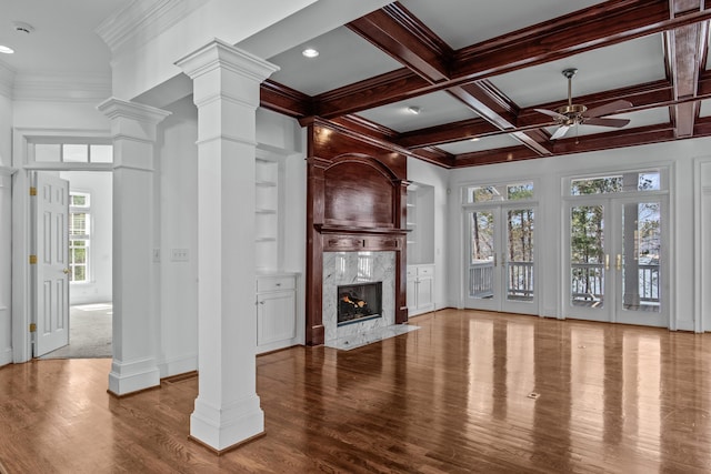 unfurnished living room featuring a fireplace, decorative columns, wood finished floors, coffered ceiling, and beamed ceiling