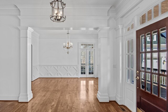 foyer featuring french doors, visible vents, an inviting chandelier, wood finished floors, and ornate columns