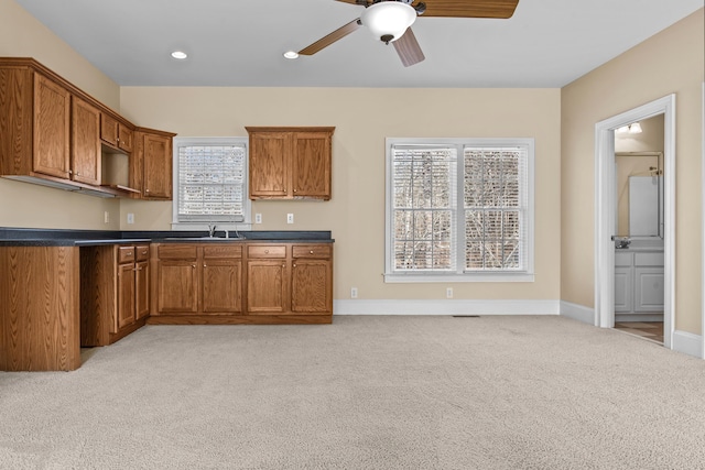 kitchen with brown cabinets, a sink, and light carpet