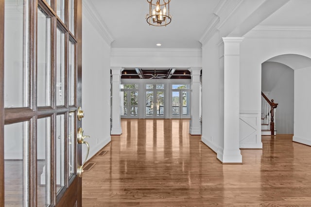 foyer entrance featuring crown molding, decorative columns, visible vents, stairway, and wood finished floors