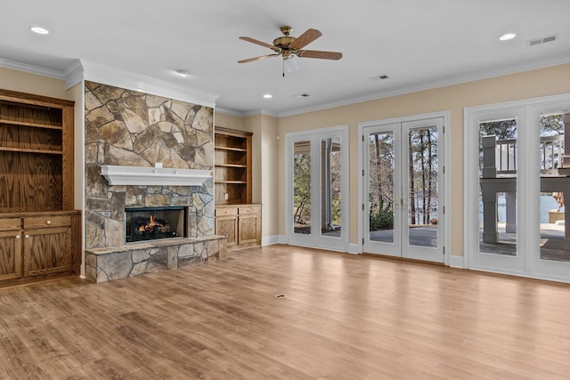 unfurnished living room featuring ornamental molding, visible vents, light wood-style floors, and a stone fireplace