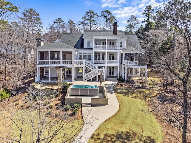 rear view of house with a yard, a chimney, stairway, a sunroom, and a patio area