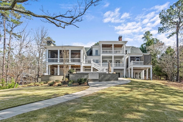 rear view of house featuring a sunroom, stairs, a chimney, and a yard