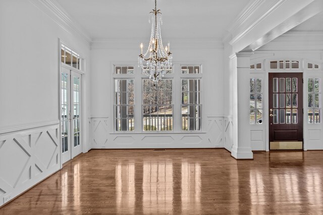 foyer entrance with a notable chandelier, wood finished floors, and crown molding