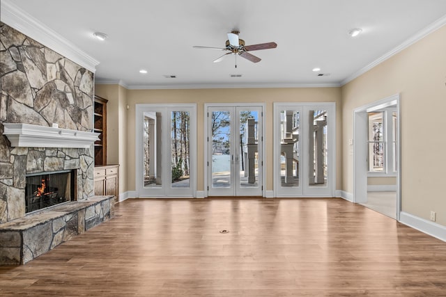 unfurnished living room featuring visible vents, wood finished floors, crown molding, french doors, and a fireplace