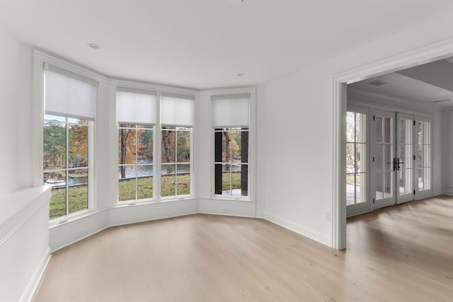 spare room with a wealth of natural light, light wood-type flooring, and french doors