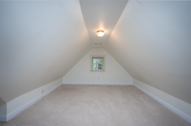 additional living space featuring vaulted ceiling and light colored carpet