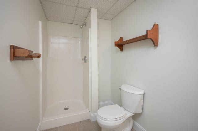 bathroom with a paneled ceiling, tile patterned floors, toilet, and walk in shower