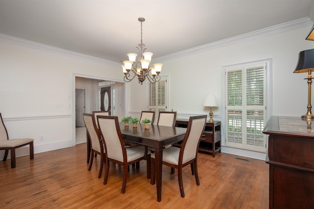 dining room featuring crown molding, wood-type flooring, and a chandelier