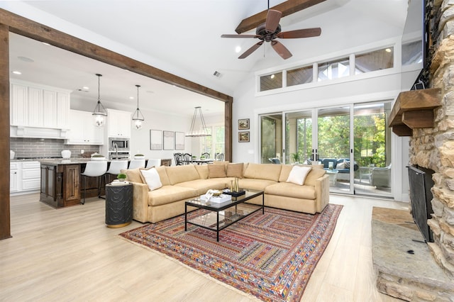 living room with a healthy amount of sunlight, a stone fireplace, and light hardwood / wood-style flooring