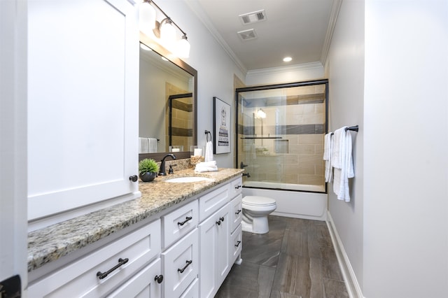 full bathroom featuring vanity, bath / shower combo with glass door, ornamental molding, and toilet