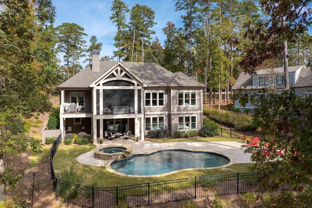 back of property with a pool with hot tub, a lawn, a patio, and a balcony