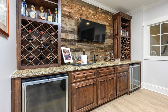 bar featuring sink, crown molding, light stone countertops, and beverage cooler