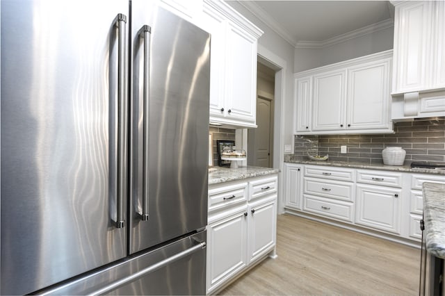 kitchen featuring crown molding, light stone counters, high end refrigerator, light hardwood / wood-style floors, and white cabinets