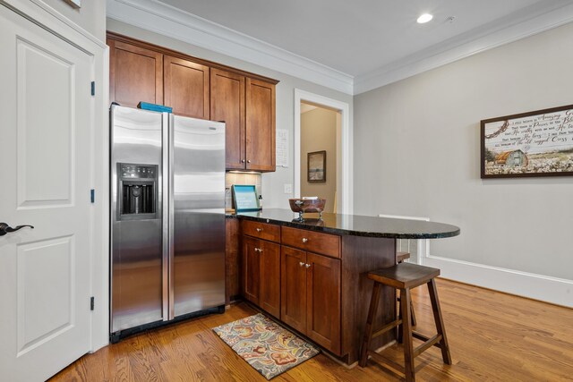 120UNIT304 Indian Summer Path, Eatonton, GA 31024 - kitchen featuring dark stone countertops, a kitchen breakfast bar, light hardwood / wood-style floors, stainless steel fridge with ice dispenser, and crown molding