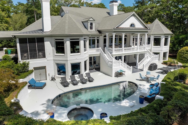 rear view of house with a swimming pool with hot tub and a patio area