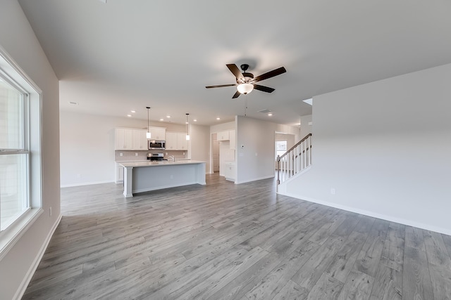 unfurnished living room with ceiling fan and light wood-type flooring