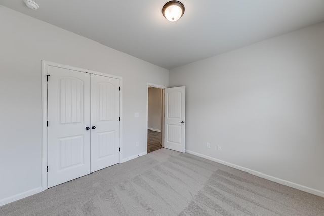 unfurnished bedroom with light colored carpet and a closet