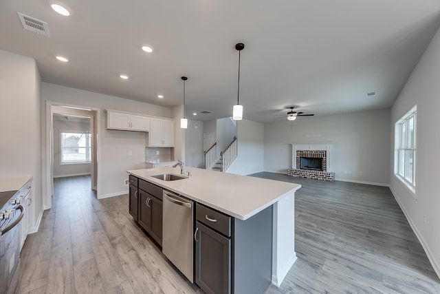 kitchen featuring sink, white cabinetry, hanging light fixtures, an island with sink, and stainless steel appliances