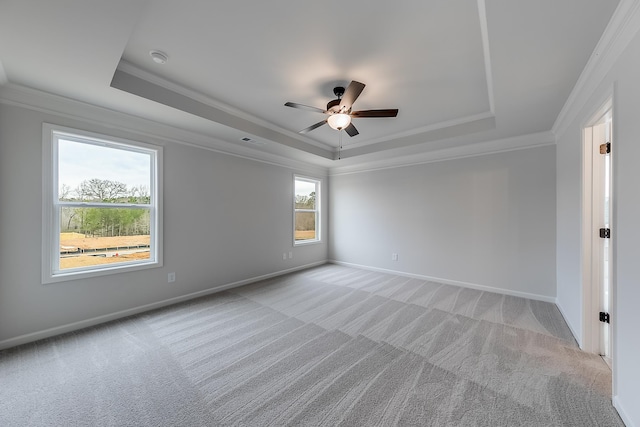 carpeted empty room featuring ceiling fan, ornamental molding, and a tray ceiling