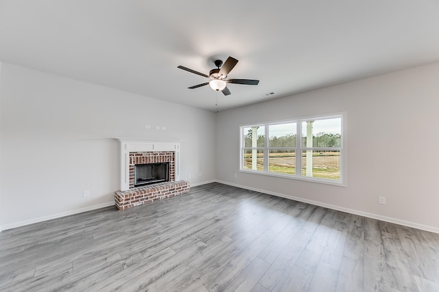 unfurnished living room featuring ceiling fan, a fireplace, and light hardwood / wood-style floors