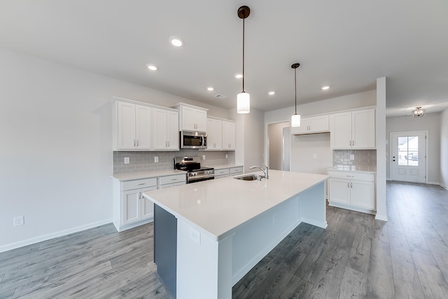 kitchen with white cabinetry, sink, hanging light fixtures, and appliances with stainless steel finishes